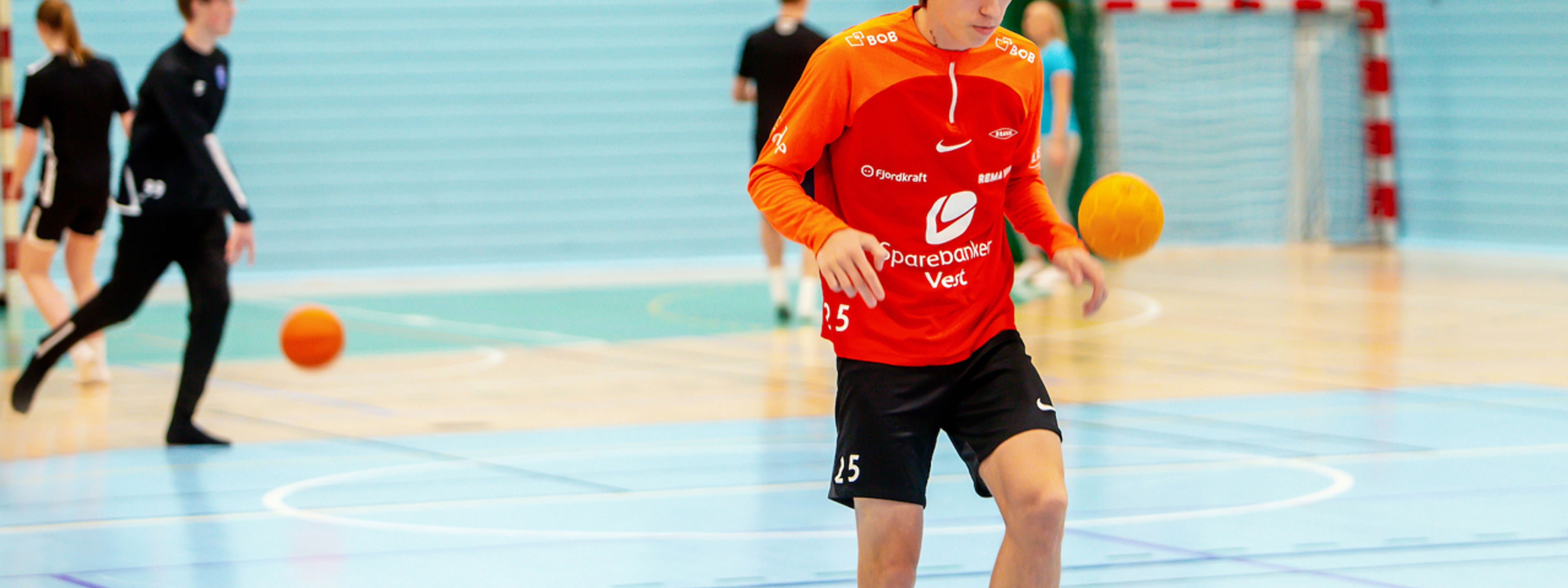 Elev som trikser med fotball inne i idrettshall